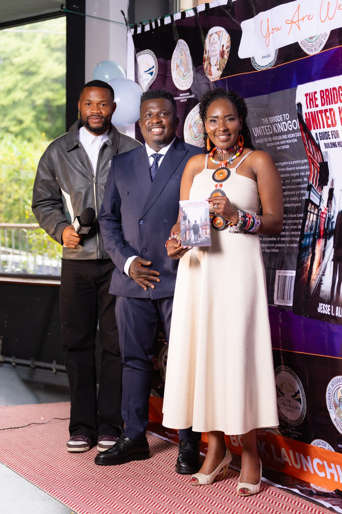 Guests holding the book and an award beside the launch banner